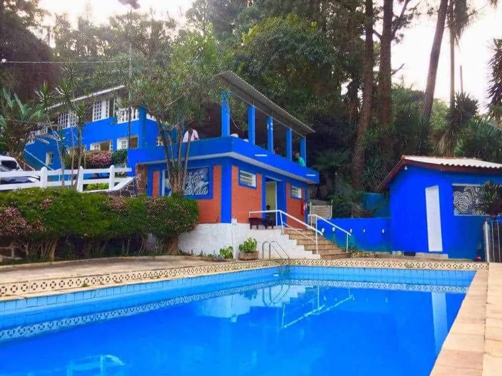Casa azul com piscina em meio à vegetação em uma unidade da clínica de recuperação do Grupo Flor de Liz